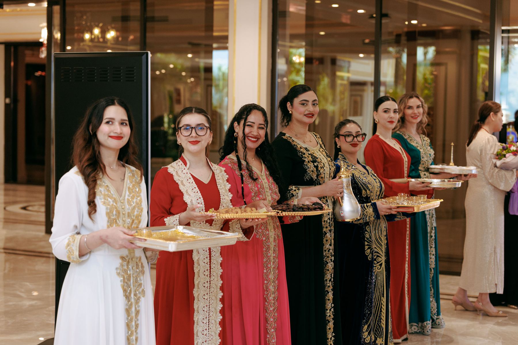 Hostesses in traditional dress serving dates and sweets